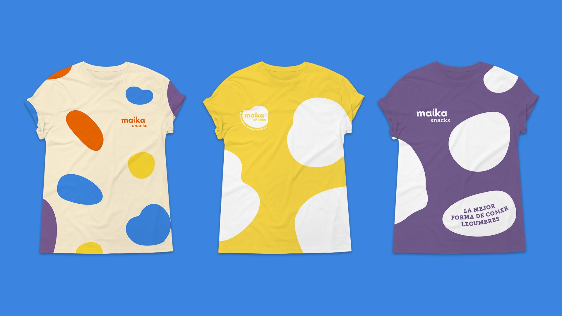 Diseño de tres poleras de Maika sobre azul: cruda con manchas de colores, amarilla con el isologo y violeta con la frase «La mejor forma de comer legumbres».