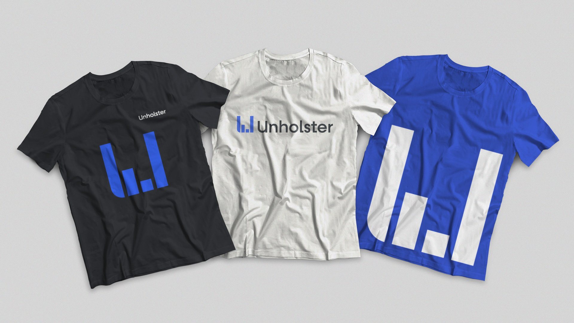 Tres poleras de Unholster: negra, blanca y azul, con el isotipo y el imagotipo.