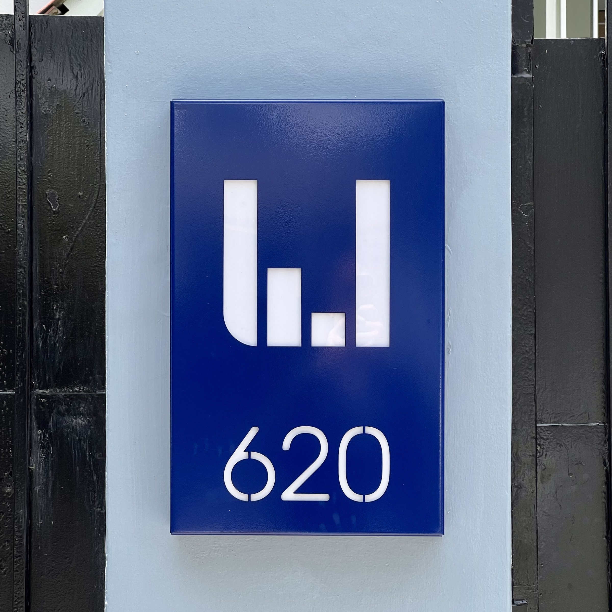 Placa de entrada de la oficina: el isotipo y el número 620 en blanco sobre azul.